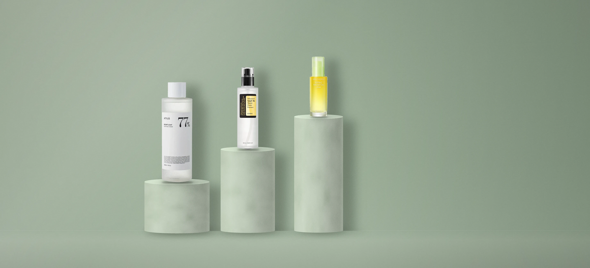 Anua toner, COSRX snail essence and Goodal vita C serum on stone pedestals, sage green set